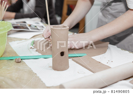 Women's hands knead clay, drawing elements of the product. Production of ceramic products at the master class on ceramics. 81490805