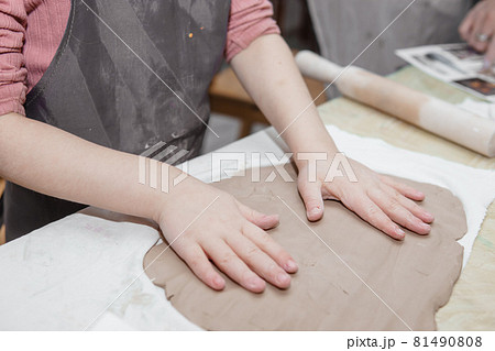 Women's hands knead clay, drawing elements of the product. Production of ceramic products at the master class on ceramics. Women's hands knead clay, drawing elements of the product. Production of ceramic products at the master class on ceramics. 81490808