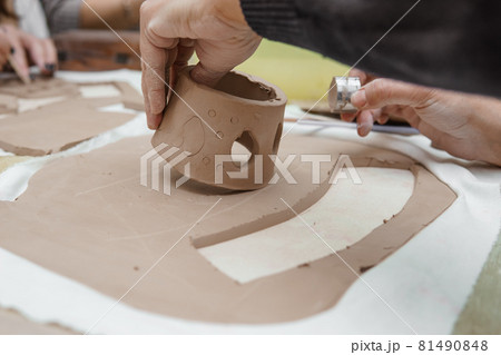 Women's hands knead clay, drawing elements of the product. Production of ceramic products at the master class on ceramics. 81490848
