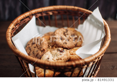 Cookies with chocolate lies in a wicker basket. A basket with gluten free cookies on a wooden table. Selective focus. Cookies with chocolate lies in a wicker basket. A basket with gluten free cookies on a wooden table. Selective focus. 81491331