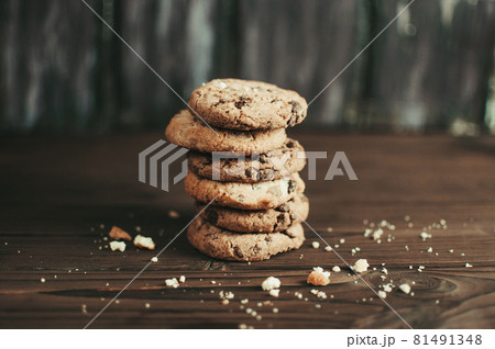 Cookies with chocolate worth a stack on a wooden table in a rustic style. Crumbs from biscuits on wooden boards. Selective focus Cookies with chocolate worth a stack on a wooden table in a rustic style. Crumbs from biscuits on wooden boards. Selective focus 81491348