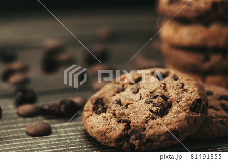 A stack of oatmeal cookies with chocolate pieces and candied fruits lies on a wooden table. Rustic table. Vintage toning. Dietary useful cookies without gluten. Copy space. 81491355