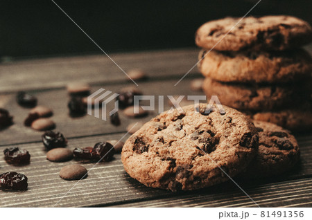 A stack of oatmeal cookies with chocolate pieces and candied fruits lies on a wooden table. Rustic table. Vintage toning. Dietary useful cookies without gluten. Copy space. 81491356