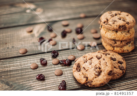A stack of oatmeal cookies with chocolate pieces and candied fruits lies on a wooden table. Rustic table. Vintage toning. Dietary useful cookies without gluten. Copy space. 81491357