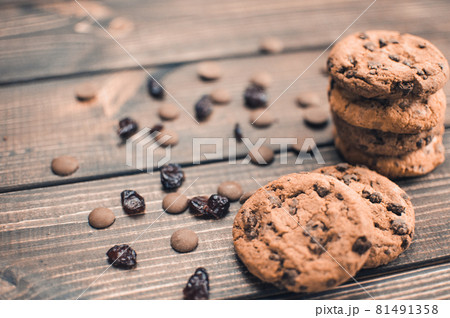 A stack of oatmeal cookies with chocolate pieces and candied fruits lies on a wooden table. Rustic table. Vintage toning. Dietary useful cookies without gluten. Copy space. 81491358