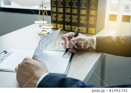 Lawyer hand holding pen and providing legal consult business dispute service at the office with justice scale and gavel hammer 81491742