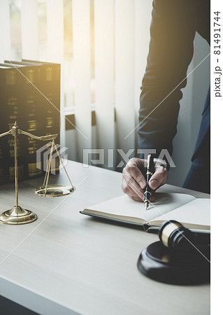 Lawyer hand holding pen and providing legal consult business dispute service at the office with justice scale and gavel hammer Lawyer hand holding pen and providing legal consult business dispute service at the office with justice scale and gavel hammer 81491744
