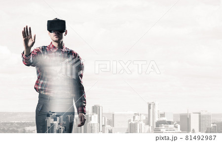 Guy wearing checked shirt and virtual mask stretching hand to touch something 81492987
