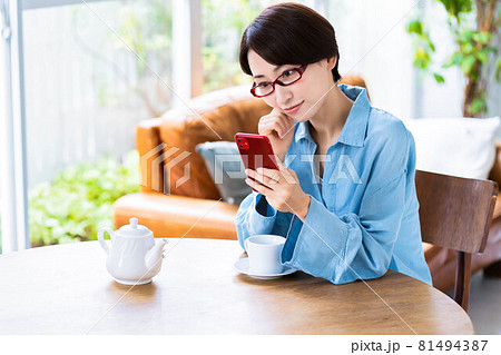 リビングで紅茶を飲みながらスマホを使う眼鏡のミドル女性 リビングで紅茶を飲みながらスマホを使う眼鏡のミドル女性 81494387