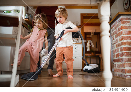 Unrecognizable father with two small children hoovering indoors at home, daily chores concept. 81494400