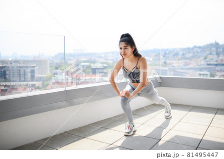 Portrait of young sport woman doing exercise on balcony outdoors in city, stretching. Portrait of young sport woman doing exercise on balcony outdoors in city, stretching. 81495447