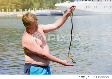 A man caught a poisonous snake while swimming in the water, holds it by the tail A man caught a poisonous snake while swimming in the water, holds it by the tail 81496099
