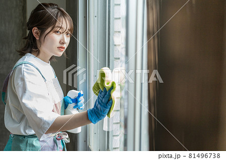 窓に洗剤を吹き付けながら拭き掃除をする女性 81496738