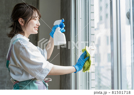 窓に洗剤を吹き付けながら拭き掃除をする女性 81501718
