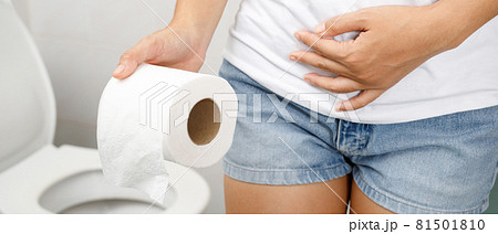 portrait of a woman suffers from diarrhea his stomach painful. ache and problem. hand hold tissue paper roll in front of toilet bowl. constipation in bathroom. Hygiene, health care concept. 81501810