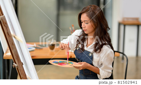 Talented asian female artist painting on canvas easel Talented asian female artist painting on canvas easel 81502941