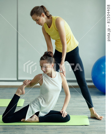 Good shape female Yoga master helps the newcomer student to practice basic gesture and correct to body pose. Concept for learning new skill in class for health and mind 81504408