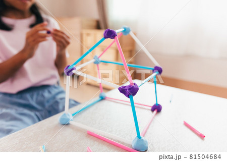 Cute asian child girl playing and creating with playdough and straws. Child concentrated with playdough building a molecule model. Kid and craft with recycle things. 81504684