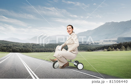 Beautiful young woman riding children's bicycle 81506440