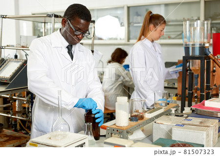 Focused man lab technician in glasses working with reagents and test tubes Focused man lab technician in glasses working with reagents and test tubes 81507323