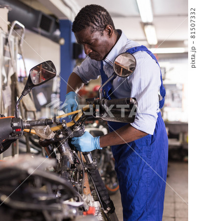 Service engineer repairing motorcycle in motorcycle service Service engineer repairing motorcycle in motorcycle service 81507332
