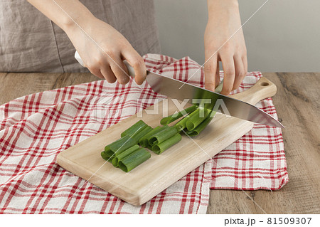 cutting green onion with a knife on the cutting board cutting green onion with a knife on the cutting board 81509307