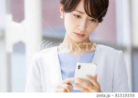 手に持ったスマホを見てネガティブな表情を見せる女性 手に持ったスマホを見てネガティブな表情を見せる女性 81510350