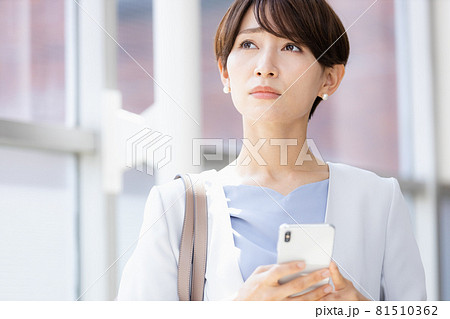 手に持ったスマホを見てネガティブな表情を見せる女性 81510362