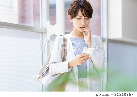 手に持ったスマホを見てネガティブな表情を見せる女性 81510367