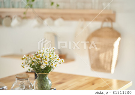 Beautiful white daisy flowers in a glass vase on the kitchen table near the window. Flower arrangement in the home interior, decor. High quality photo 81511230