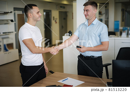 Men shake hands after successful sale in car showroom 81513220