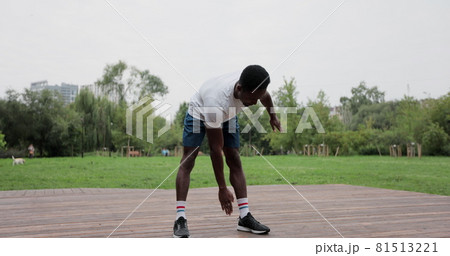 African american man warming up with exercises before intense workout outdoors. Warm-up of muscles before jogging. Outdoor sports. African american man warming up with exercises before intense workout outdoors. Warm-up of muscles before jogging. Outdoor sports. 81513221