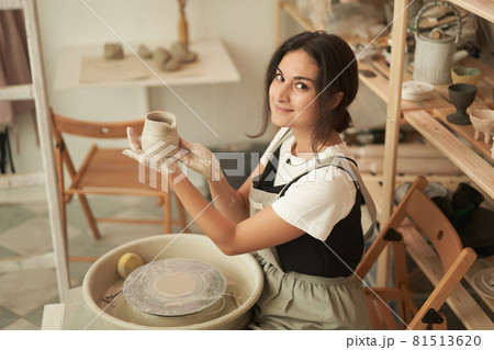 Woman showing handmade clay pot in workshop Woman showing handmade clay pot in workshop 81513620