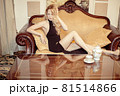 Beautiful young adult blond woman sitting on sofa Beautiful young adult blond woman sitting on sofa 81514866