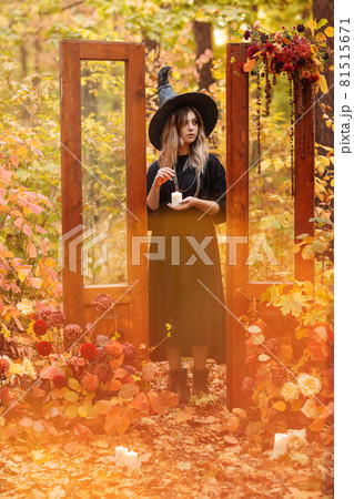 Witch costume and hat looking mysteriously at candle in her hands 81515671
