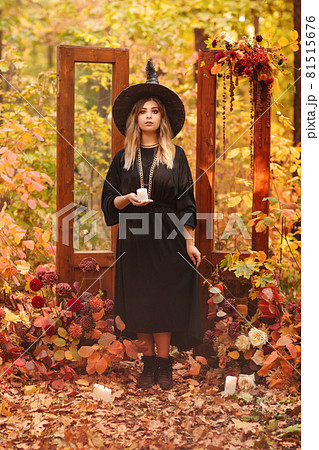 Witch costume and hat looking mysteriously at candle in her hands Witch costume and hat looking mysteriously at candle in her hands 81515676