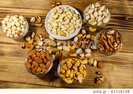 Assortment of nuts on wooden table. Almond, hazelnut, pistachio, peanut, walnut and cashew in small bowls. Top view. Healthy eating concept 81516188
