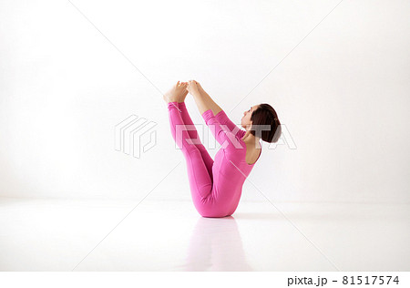 Young slender woman in pink long bodysuit performing yoga Boat Navasana pose Young slender woman in pink long bodysuit performing yoga Boat Navasana pose 81517574