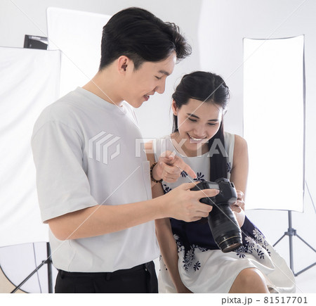 Asian man photographer lets models view pictures taken on camera dslr screen.  Photography and model smiling happy in the white room at the studio. Concept camera photograher picture. 81517701