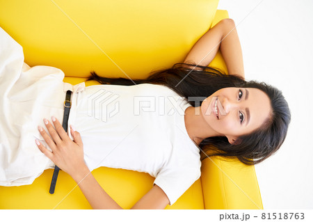Top view of smiling pretty asian woman relaxing on yellow sofa 81518763