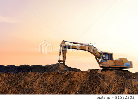 Excavator during earthmoving work at open-pit mining on sunset background.  81522203