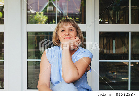 Happy senior woman smiling at camera while sitting on terrace of her country house 81522537