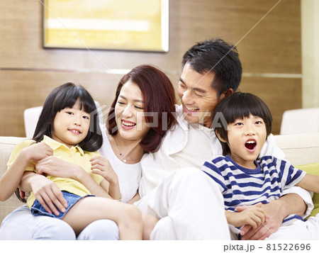 portrait of a happy asian family sitting on couch at home, smiling and laughing 81522696