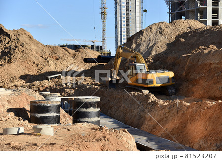 Laying heating pipes in trench at construction site.  81523207