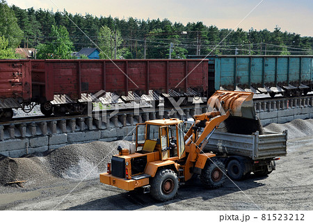 Wheel loader load gravel into a dump truck at a cargo railway station. Wheel loader load gravel into a dump truck at a cargo railway station. 81523212