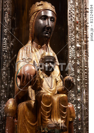 Montserrat, Spain - April 5, 2019: 12th century statue of Black Madonna of Montserrat in cathedral of Montserrat Monastery. She is protected glass cover with orb protruding for pilgrims to touch 81524694