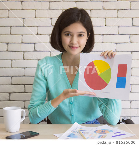 Half race Thai-German short hair cute girl holding paper of business graph and chart to present and show for online conference Half race Thai-German short hair cute girl holding paper of business graph and chart to present and show for online conference 81525600