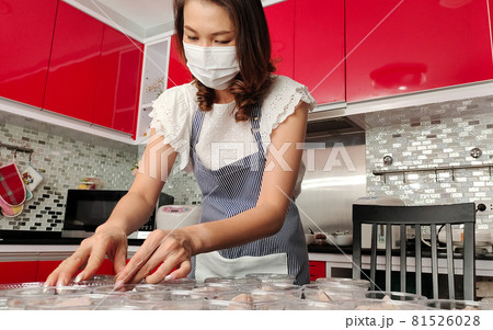 Beautiful Asian housewife wearing protective mask prepares set of banana in coconut milk, famous native Thai style dessert, for sale and delivery to customers for income during coronavirus quarantine 81526028