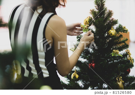 Back view of woman decorating and arranging Christmas tree at home and preparing for winter holidays with calm circumstance 81526580
