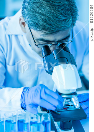 Doctor or researcher wearing eyeglasses and blue medical glove concentrate looking to a microscope during working in lab. Doctor or researcher wearing eyeglasses and blue medical glove concentrate looking to a microscope during working in lab. 81526584